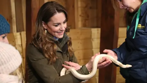 PA Media The duchess holds a snake while visiting Ark Open Farm in Newtownards