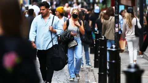 Getty Images Woman in a mask on a busy London street