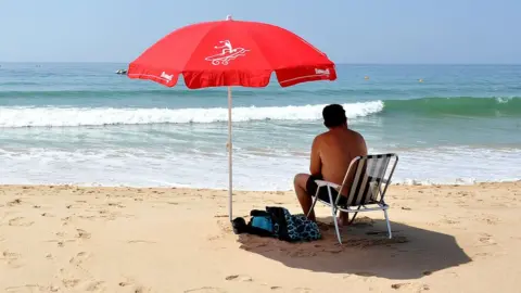 PA Media Man on beach at Praia da Luz in Portugal