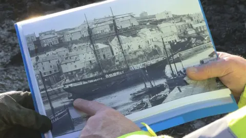 BBC Mallory Haas and Peter Holt looking at an old photo of the John Sims