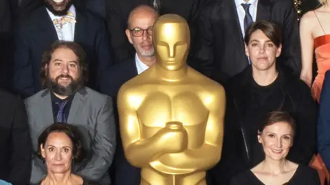 Todd Wawrychuk Eric Fellner hiding behind the Oscars statuette