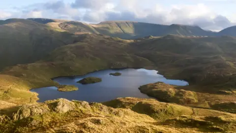 Getty Images Aerial view of a tarn surrounded by hills