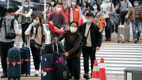 Getty Images Chinese travellers wearing masks at the airport