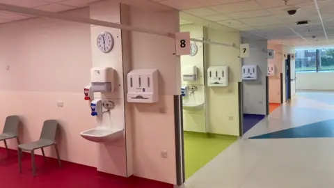LDRS A series of beds in a hospital ward, each with different coloured, pastel walls