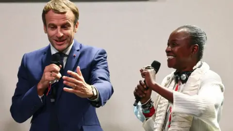 AFP Cameroonian-born curator Koyo Kouoh (R) and French President Emmanuel Macron speak at a conference about the restitution of African heritage at the Africa-France summit in Montpellier, France 8 October 2021