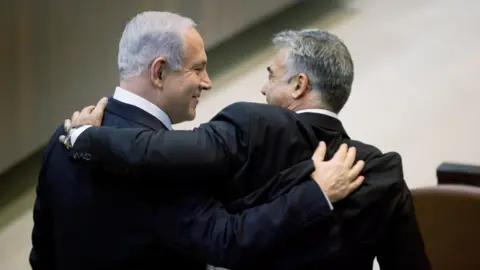 Getty Images Benjamin Netanyahu (L) hugs Yair Lapid (R) during a Knesset session on 18 March 2013 in Jerusalem