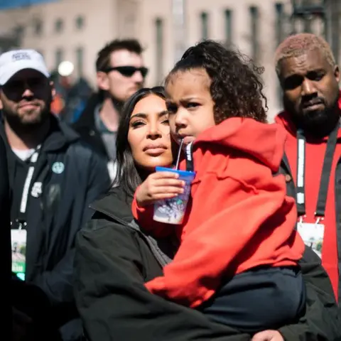 SOPA Images Kardashian, Holding North, with Kanye in background at event