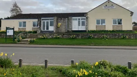 Sedgemoor District Council A village hall by a road with daffodils outside