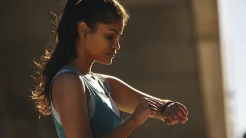 Getty Images A woman looking at a sports watch