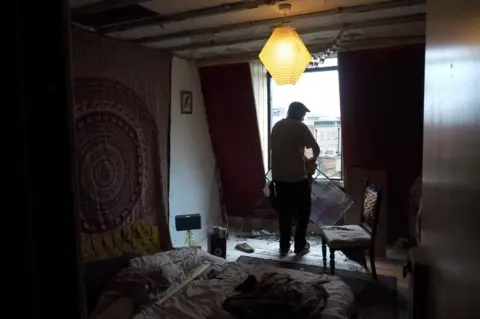 Ed Gold A man holding a window pane in a darkened room