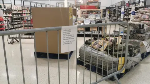 PA Media A notice informing customers of the sales of non-essential products at a Tesco Extra store in Pengam Green, Wales