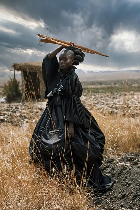 Tamary Kudita Portrait of a young woman dressed in a Victorian dress and holding traditional Shona cooking utensils