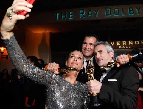 Getty Images Molly Sims and Scott Stuber with Alfonso Cuaron and his three Oscars in 2019