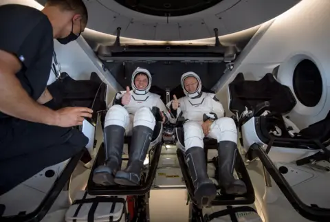 NASA/Bill Ingalls/Handout via EPA Astronauts Robert Behnken and Douglas Hurley give a thumbs up as they sit inside the SpaceX Crew Dragon Endeavour spacecraft