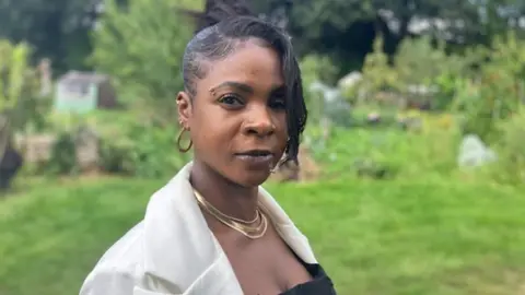 Woman looks at camera with garden in background