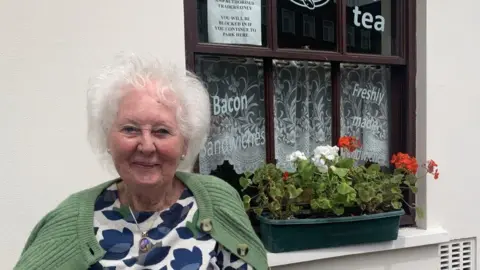 Chairperson Caroline Lewis smiling outside the Market Square café in Pontypool