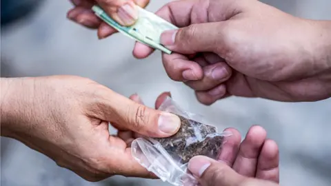 Getty Images two sets of a hands exchanging cannabis for cash