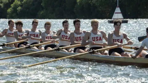 Warner Bros/Laurie Sparham A still from the film showing the cast rowing