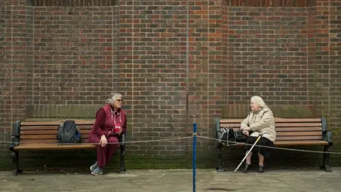 AFP Two women observe social distancing measures in York