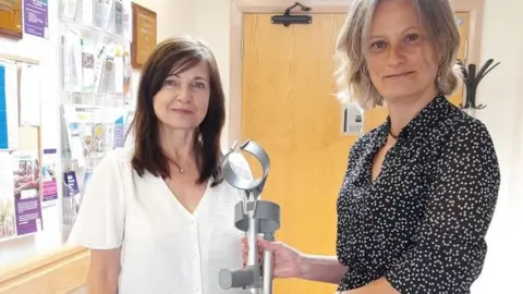 IOM GOV Hilary Yates and Claire Bader with a pair of crutches