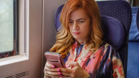 Woman sitting on train looking at her phone