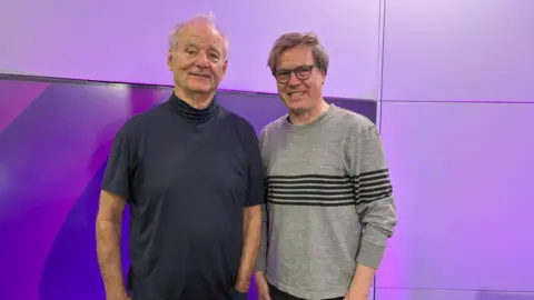 Murray and Jan Vogler in the BBC WM studio. Mr Vogler is wearing a grey jumper with black horizontal stripes. He has brown hair and round glasses.