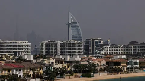 Getty Images An empty beach with a number of residential buildings along the waterfront and high rise buildings behind them. 