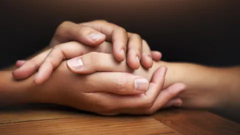 Getty Images Hand being held across a table