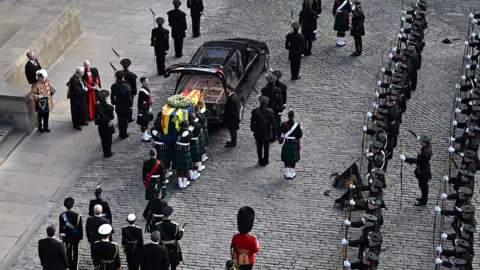 OLI SCARFF/AFP Pallbearers prepare to carry the coffin of Queen Elizabeth II, draped in the Royal Standard of Scotland, into St Giles' Cathedral