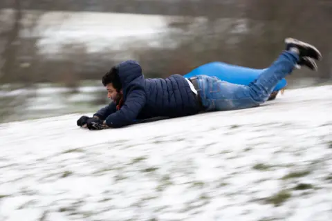 PA Media A man sleds down Primrose Hill in London, on 8 February 2021