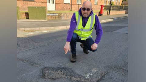 Nigel Jones pointing at a pothole in the road