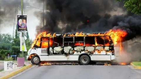 Reuters A burning bus, set alight by cartel gunmen to block a road, is pictured during clashes in Culiacán