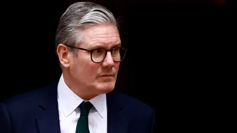 Getty Images A head-and-shoulders picture of Keir Starmer. He is wearing a dark blue suite, a white shirt and a dark tie. He has a serious expression on his face. He is pictured against a dark background. 