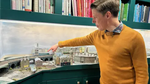 Julia Bryson/BBC Michael Scott with the model railway town of Chandwell