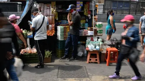 AFP People wear face masks in a market as a preventive measure against the spread of the new coronavirus, COVID-19, at the Petare neighborhood in Caracas, on April 2, 2020