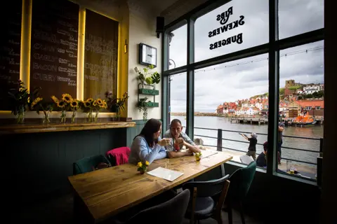 Ceri Oakes/BBC Emma Morley and Lee Clarke from Peterborough, drinking at The Moon and Sixpence, Whitby. 4 July 2020