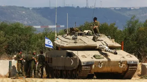 Reuters Israeli troops and a tank deployed near Israeli's border with Lebanon (16 October 2023)