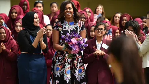 Getty Images S First Lady Michelle Obama holds flowers as she is received by young students holding the American flag in the courtyard before an event as part of the 'Let Girls Learn Initiative' at the Mulberry School for Girls on June 16, 2015 in London,