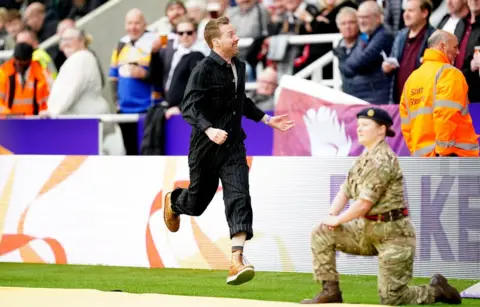 PA Media Ricky Wilson of The Kaiser Chiefs entertains the crowd during a delay to the Rugby League World Cup group A match at St James' Park, Newcastle