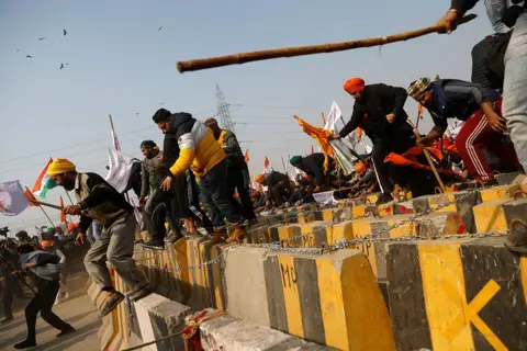 REUTERS/Danish Siddiqui Farmers cross a barricade