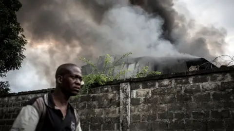 Getty/JOHN WESSELS Smoke burning out of the electoral commission warehouse in Kinshasa