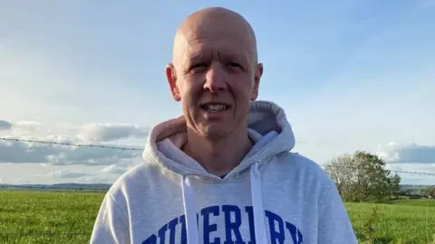 BBC A man stands in front of a field