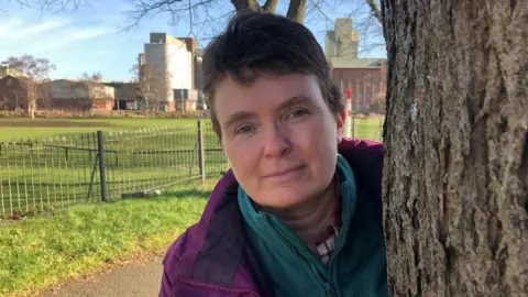 Emma Baugh/BBC Marion Turner-Hawes standing behind one of the trees