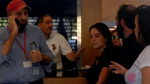 EPA A woman identifying herself as Sally Hafez (centre) takes staff hostage at the Blom Bank branch in Beirut's Sodeco area on 14 September 2022