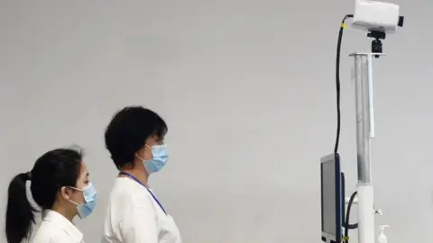 Reuters Immigration and Checkpoints Authority staff members wait for arriving passengers at a temperature screening station at the Singapore Cruise Center, following the coronavirus outbreak in Singapore