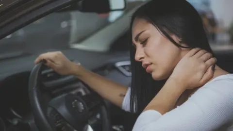 Getty Images A woman rubbing her neck after experiencing a whiplash injury in a car