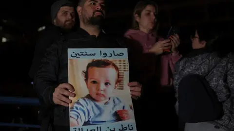 Reuters A man holds up a poster showing a victim of the Beirut port explosion, after Lebanon's public prosecutor charged the judge leading the investigation (25 January 2023)