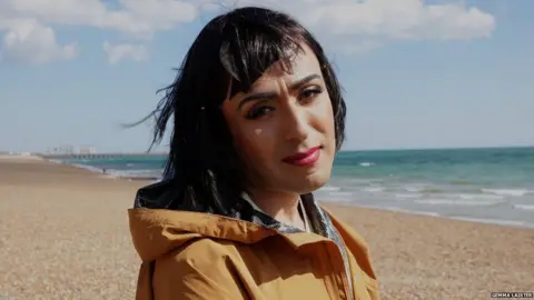 Gemma Laister Bella is on Brighton Beach, looking at the camera