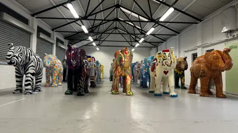 Thirty elephants in a Slough Trading Estate lined up in four. 