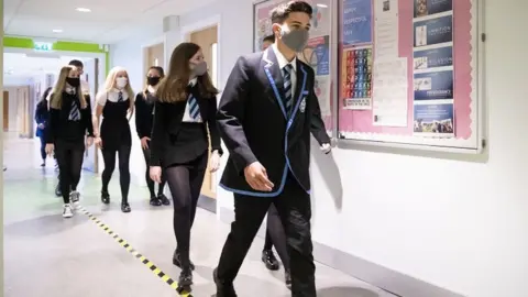 PA Media Masked pupils in school corridor